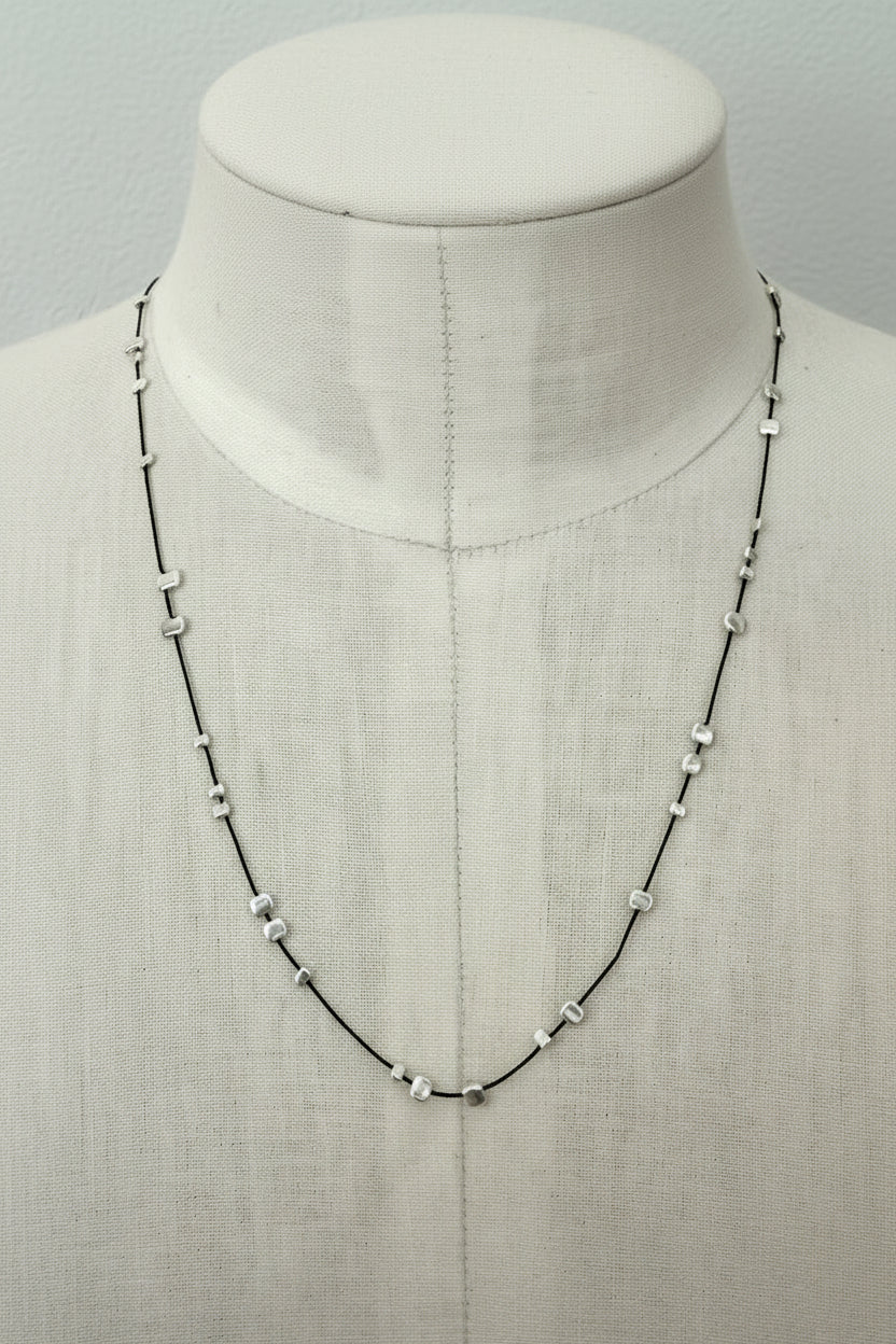 Necklace with scattered stamped silver beads on silk thread