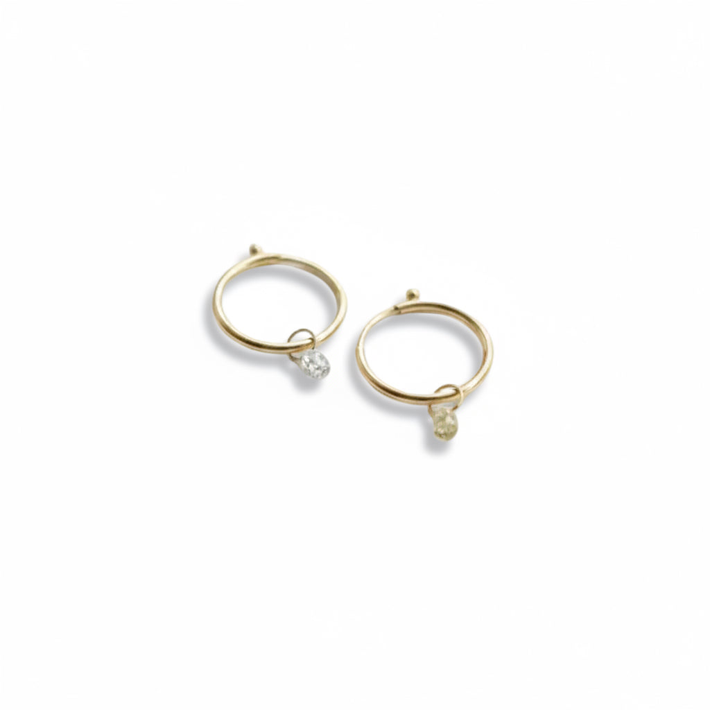 "Pair of 14K yellow gold 12mm endless hoop earrings with .20 carat diamond bead drops, styled on a dark textured background"