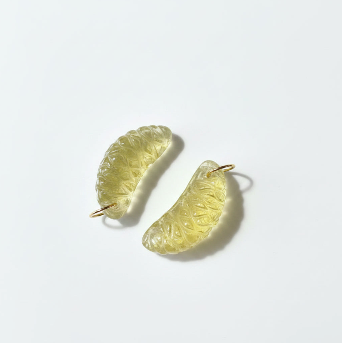 Pair of light yellow lemon-shaped earrings on a white background