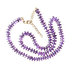 Purple beaded necklace with gold chain on a white background